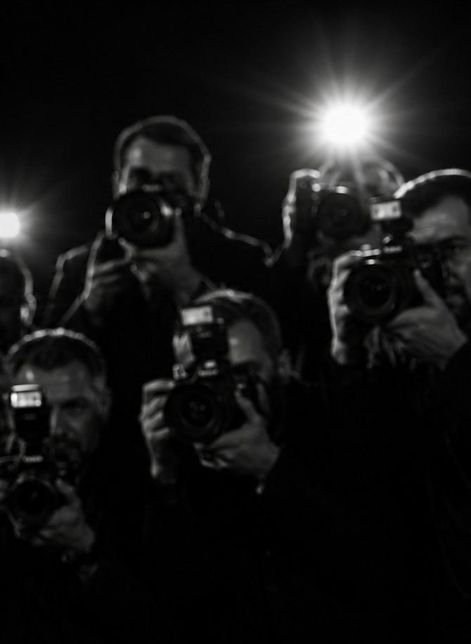 Press photographers packed shoulder to shoulder, flashguns firing